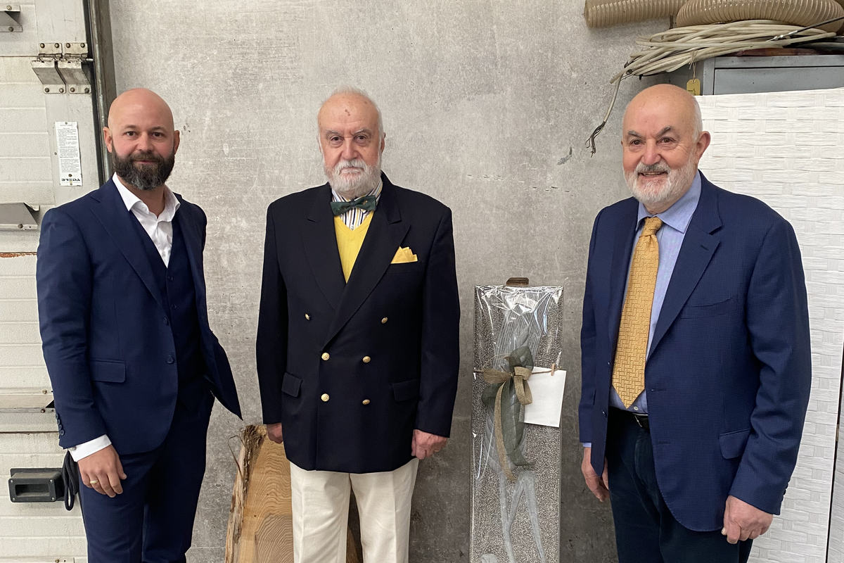 Tre persone in azienda accanto a un'opera e a una tavola di legno